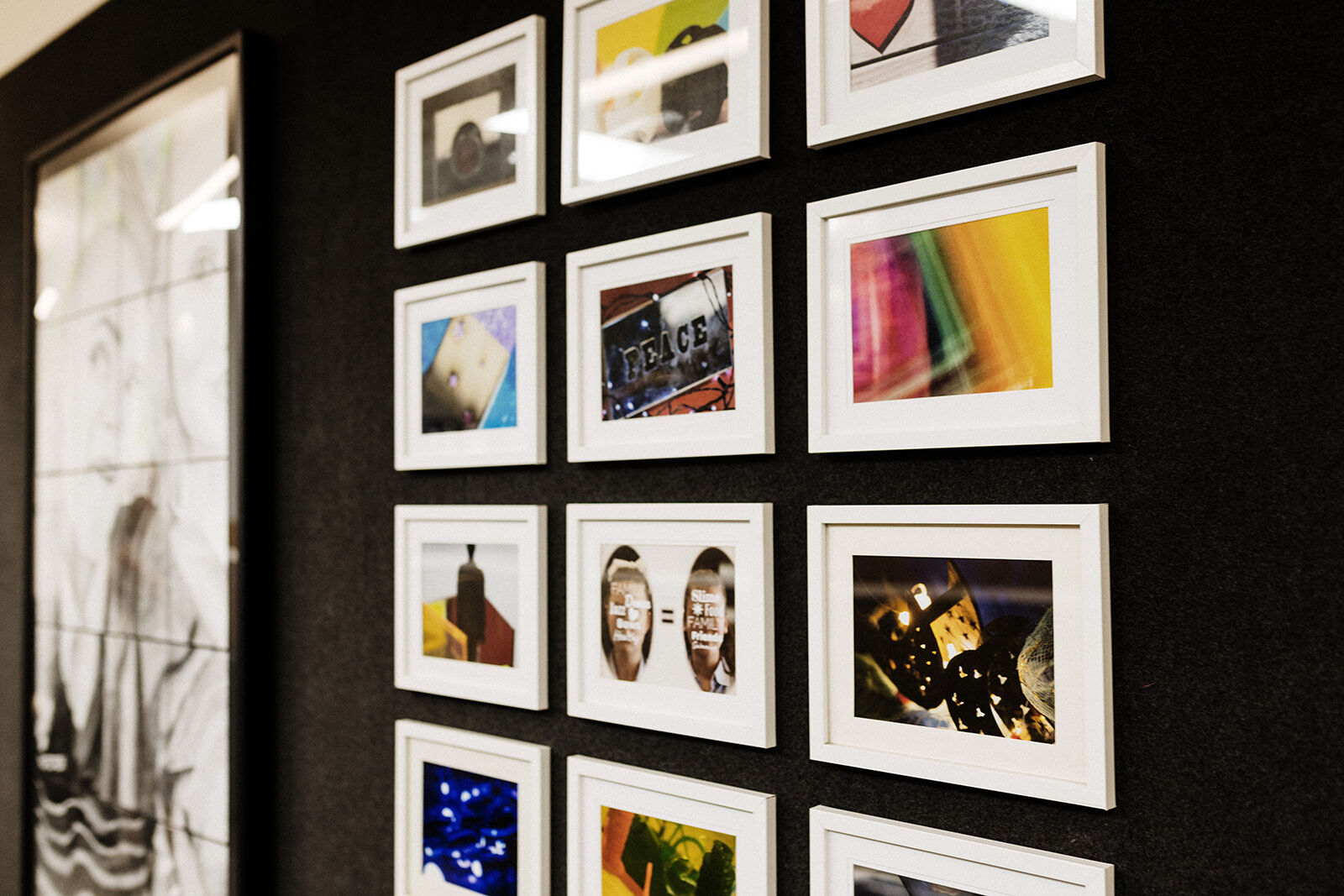 A close-up view of framed student photography art displayed on a classroom wall.