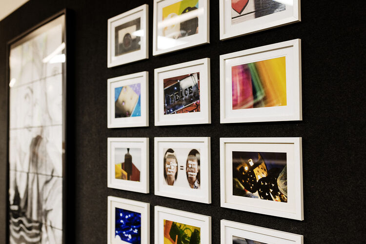 A close-up view of framed student photography art displayed on a classroom wall.