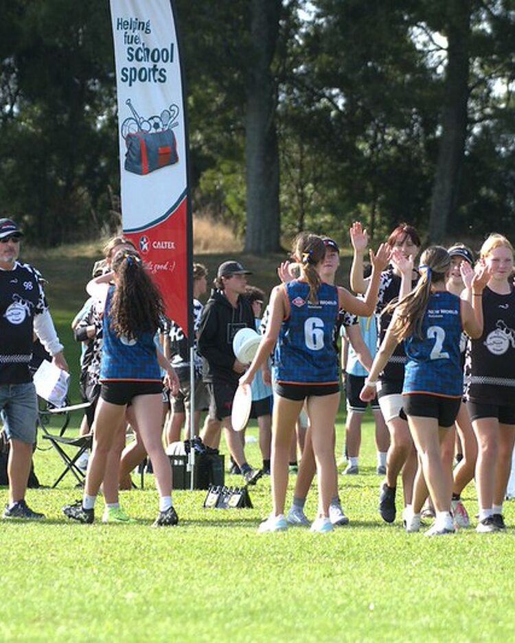 A girls’ touch rugby team from Rototuna posing together on a grassy field, with some standing and others kneeling.
