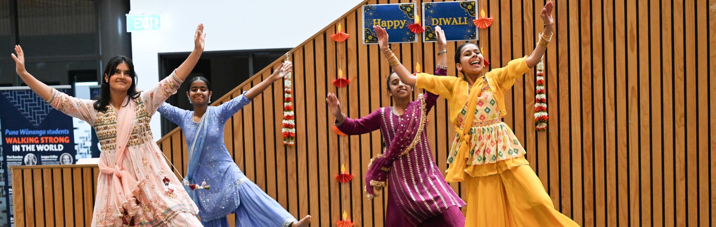 Four students performing a traditional Diwali dance in colourful Indian outfits on stage