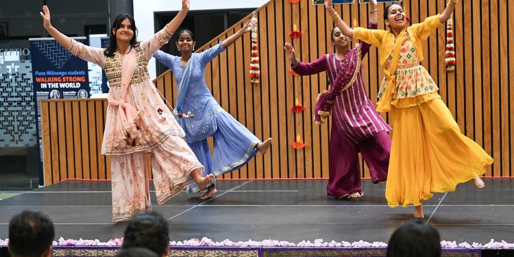 Group of students performing a traditional Indian dance on stage wearing bright and colourful cultural clothing.