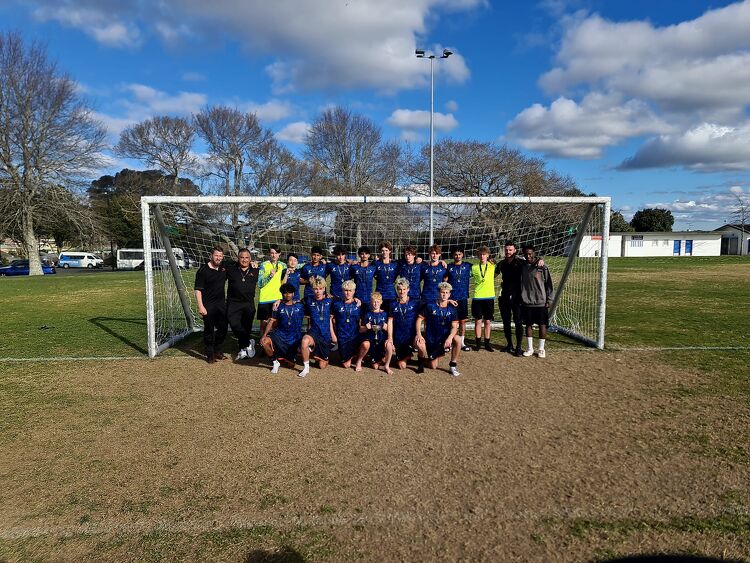 Boys football team photo in front of a goal on a grass pitch