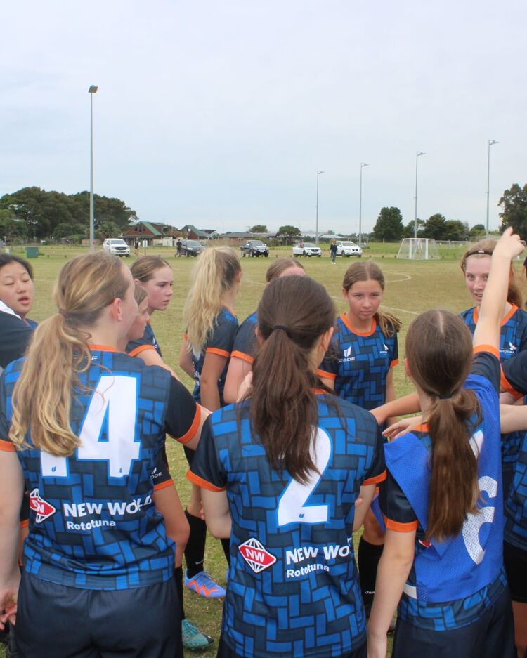 Girls football team in a huddle with a coach giving instructions