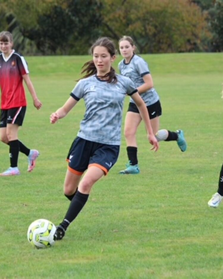Female football player running with the ball on a green field