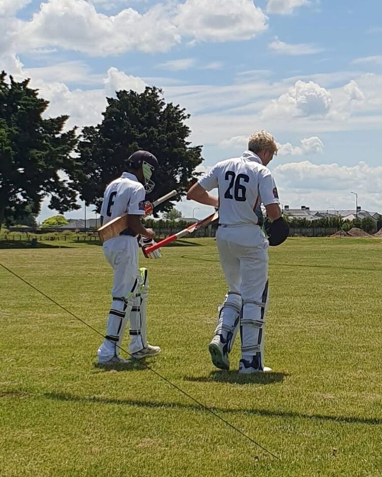 Boys cricket team smiling under a gazebo on a sunny field