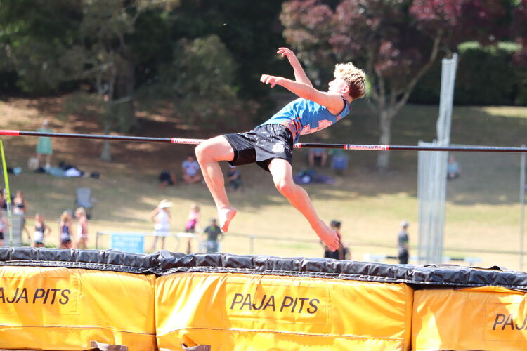 Student athlete performing a high jump over the bar during a track and field competition.