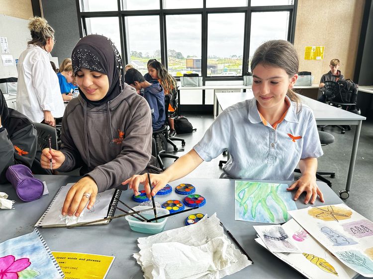 Two students working on colourful painting and art projects in a well-lit classroom at Rototuna High School.