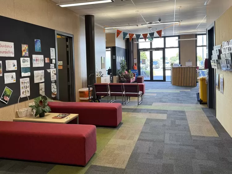 Rototuna High School's student services or counselling area with red seating, noticeboards, and guidance posters.