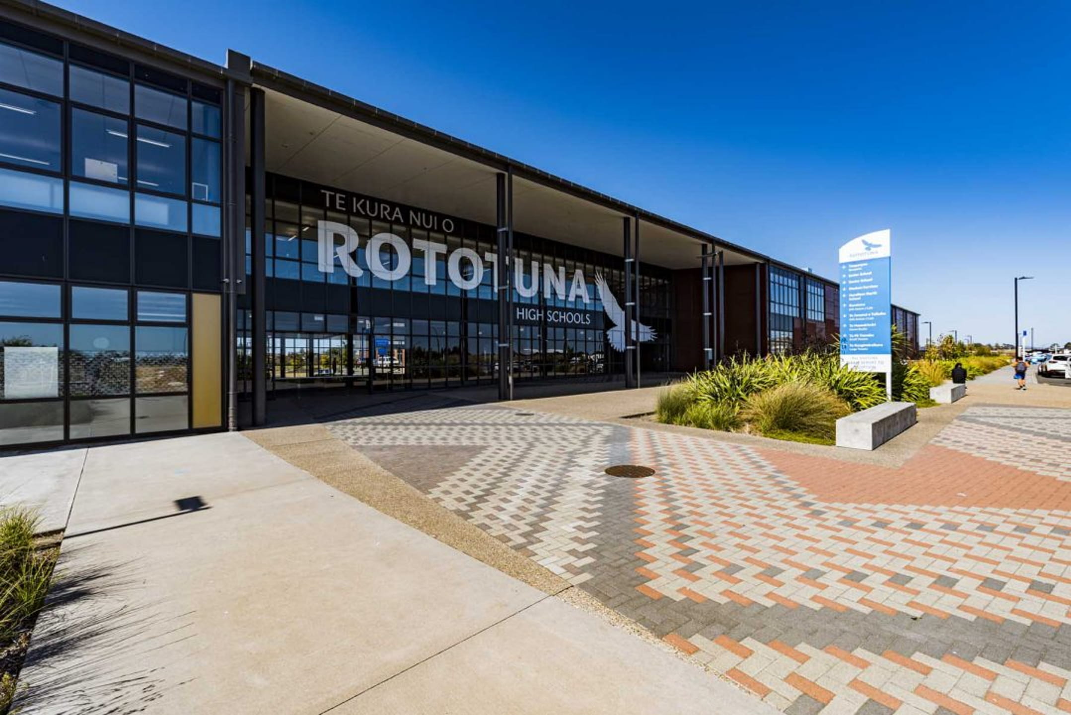 Exterior of Rototuna High Schools building showing the main entrance under a bright blue sky.